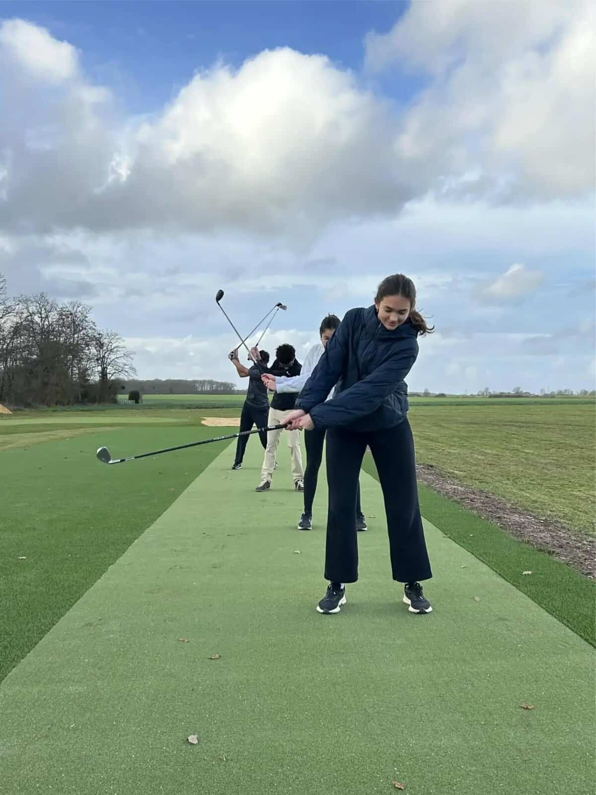 Students playing golf outdoors at a school sports facility, promoting athletic skills and outdoor activities for international students.