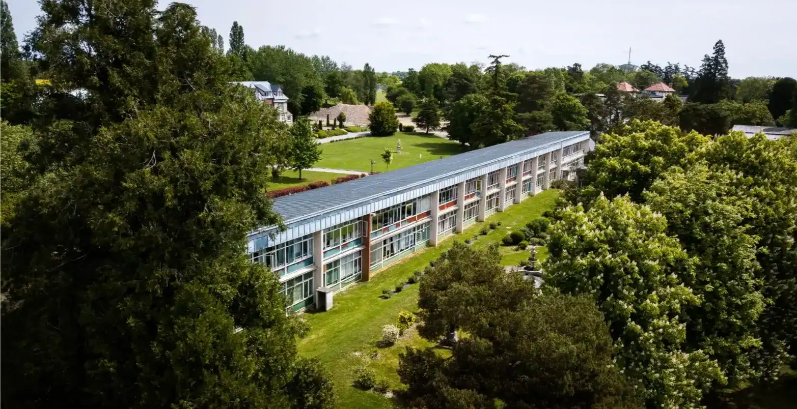 Modern school building surrounded by lush green trees and expansive gardens for optimal learning environment.