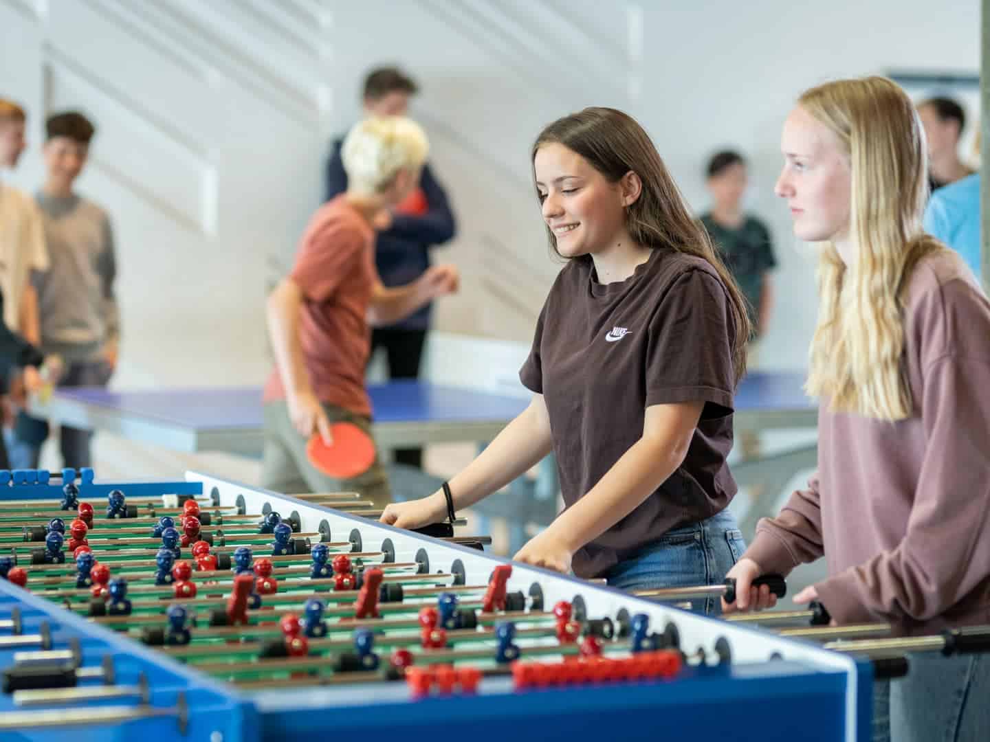 Young students playing table football at a modern international school.