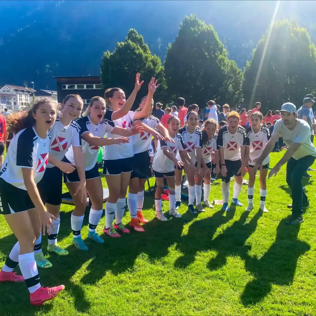 Dedicated school sports team celebrating victory outdoors on a bright sunny day at a international school event.