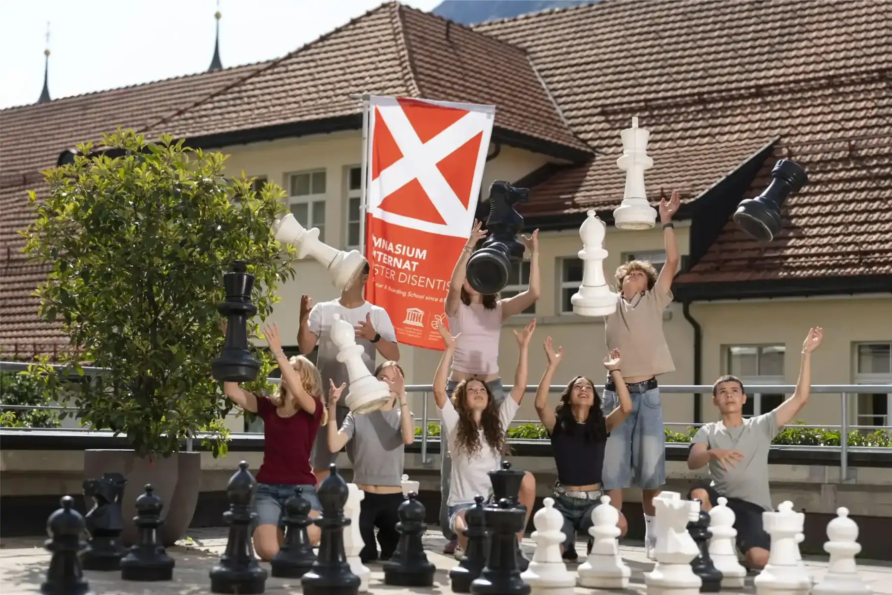 Students playing life-sized chess outdoors at a school campus.