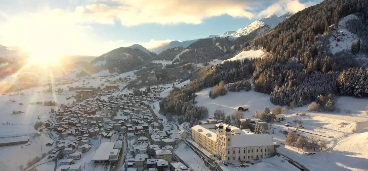 Snow-covered mountain village with a historic church and scenic winter landscape, ideal for global school immersion and cultural exchange.