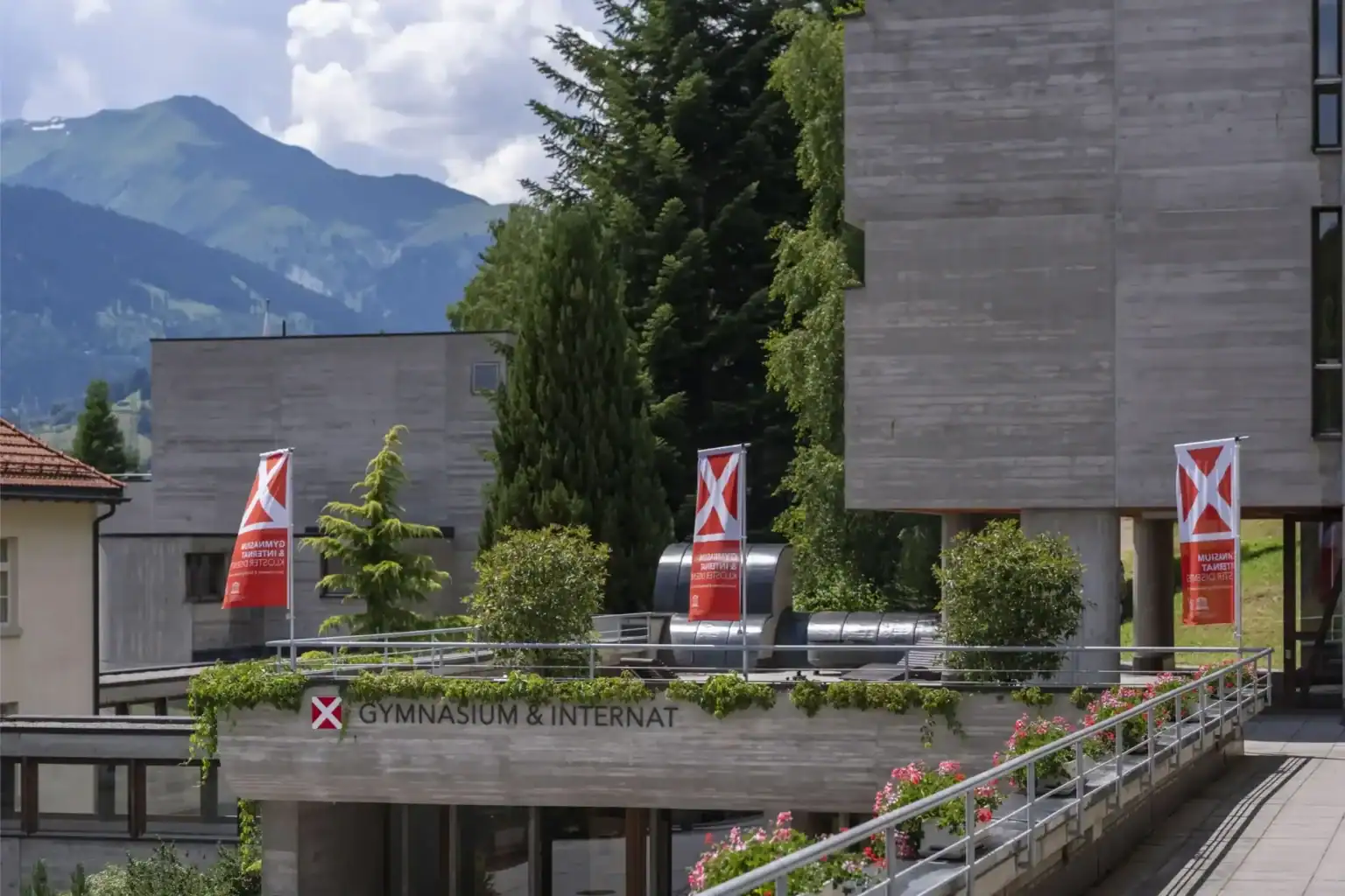Modern international school campus with gymnasium and mountains in the background for top global education.