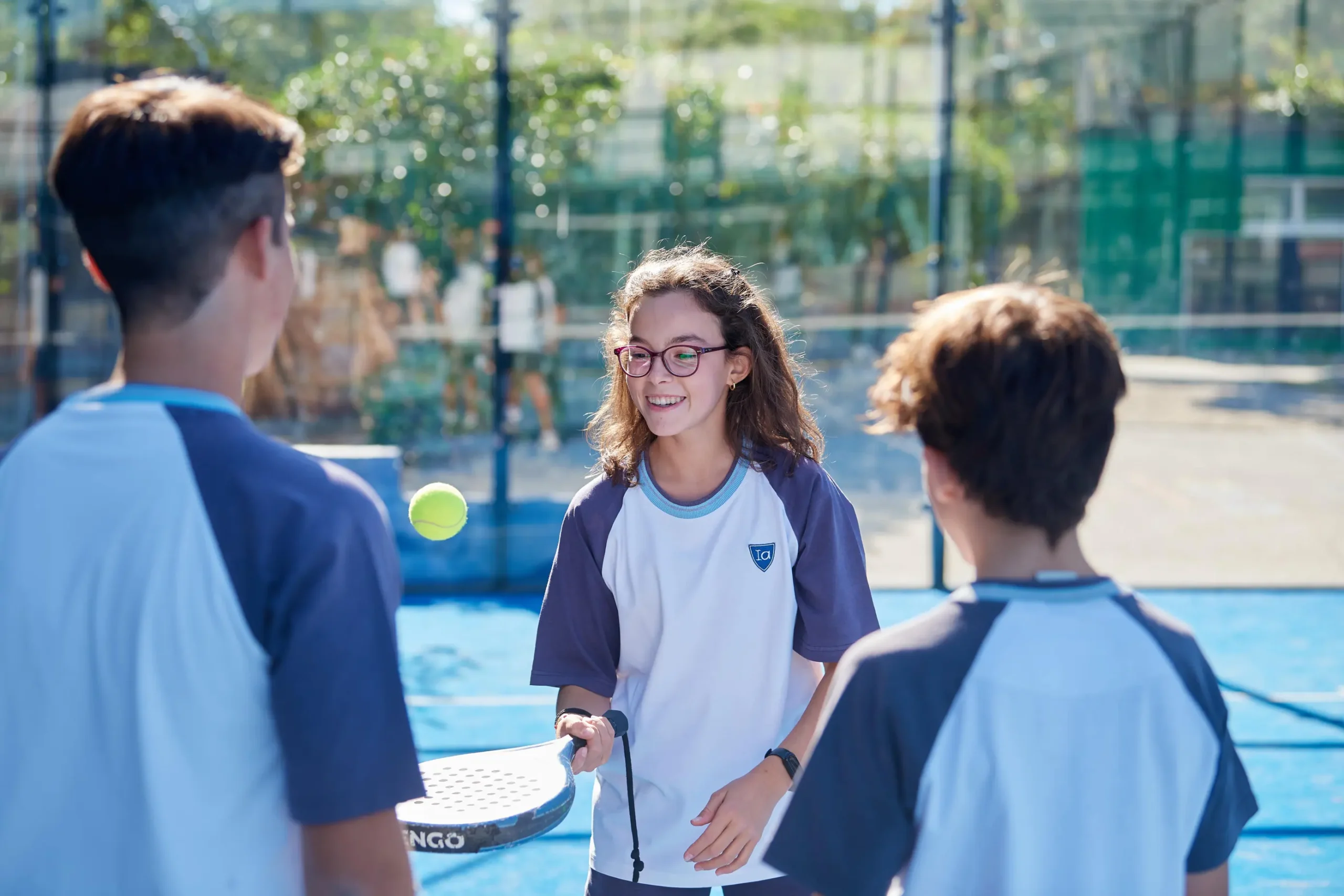 Bright-eyed students enjoying outdoor tennis at World Schools sports facility.