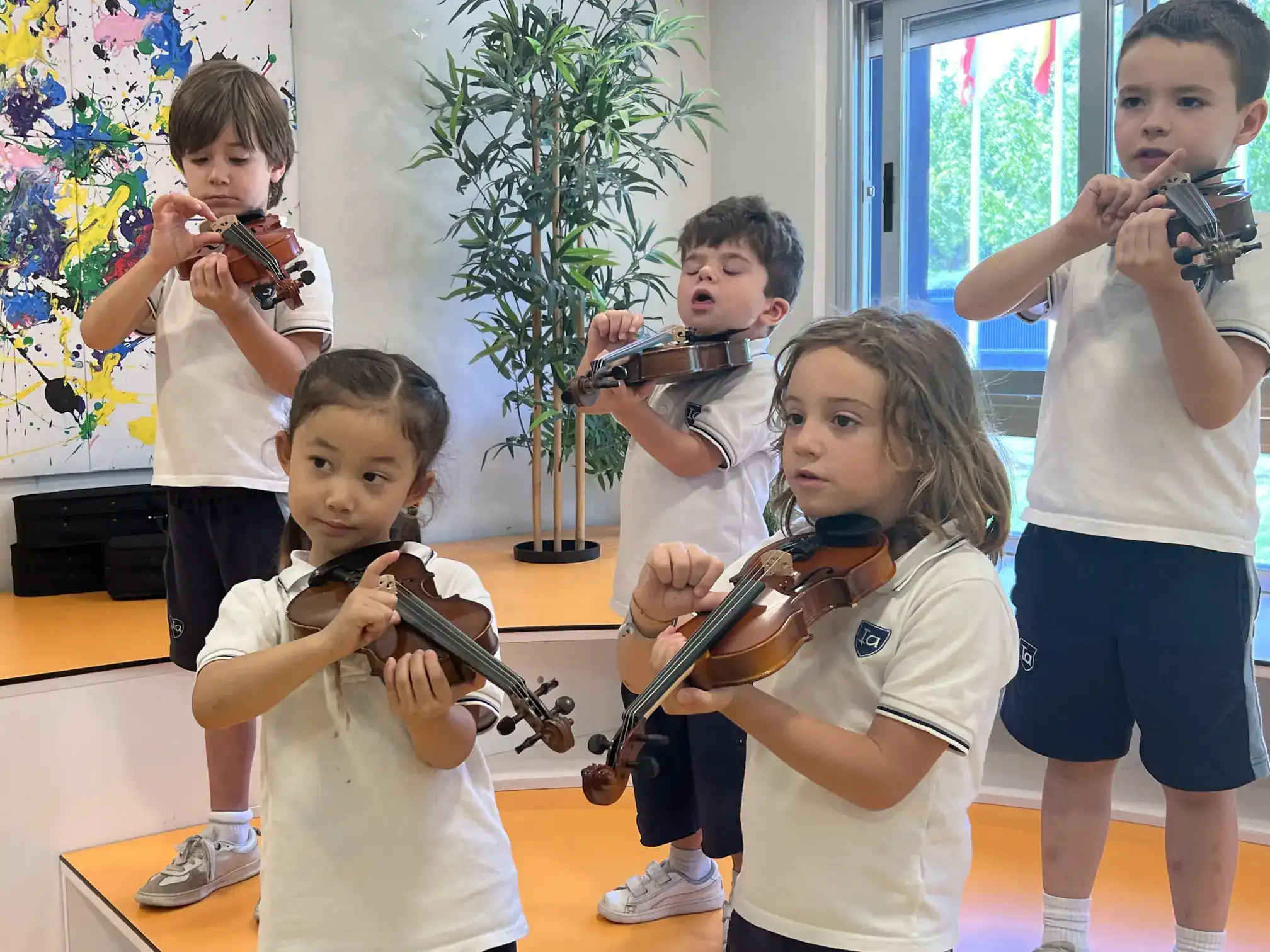 Young children playing violins in a music class at a world school, fostering arts education and musical skills development in primary students.