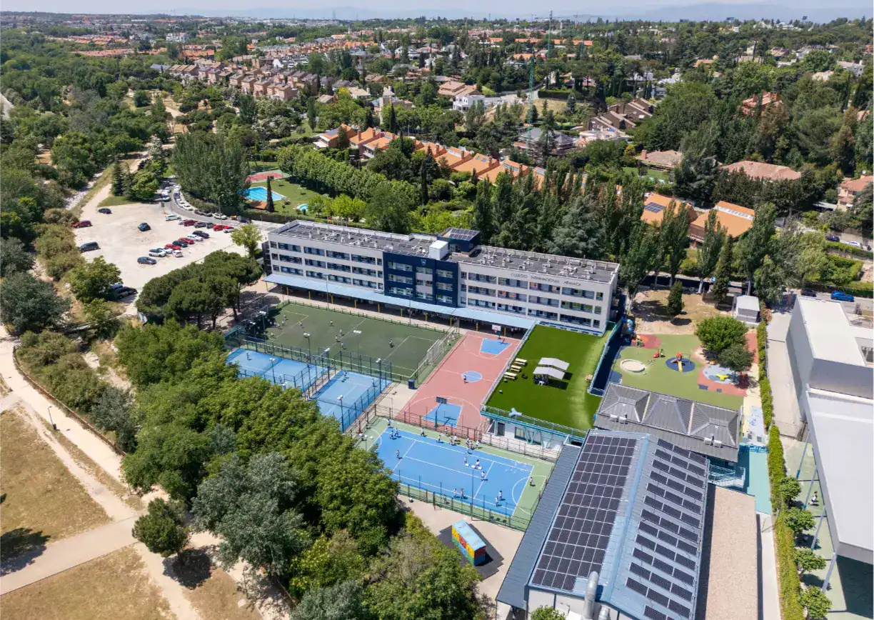 Modern international school with sports facilities and green outdoor spaces in a suburban area.