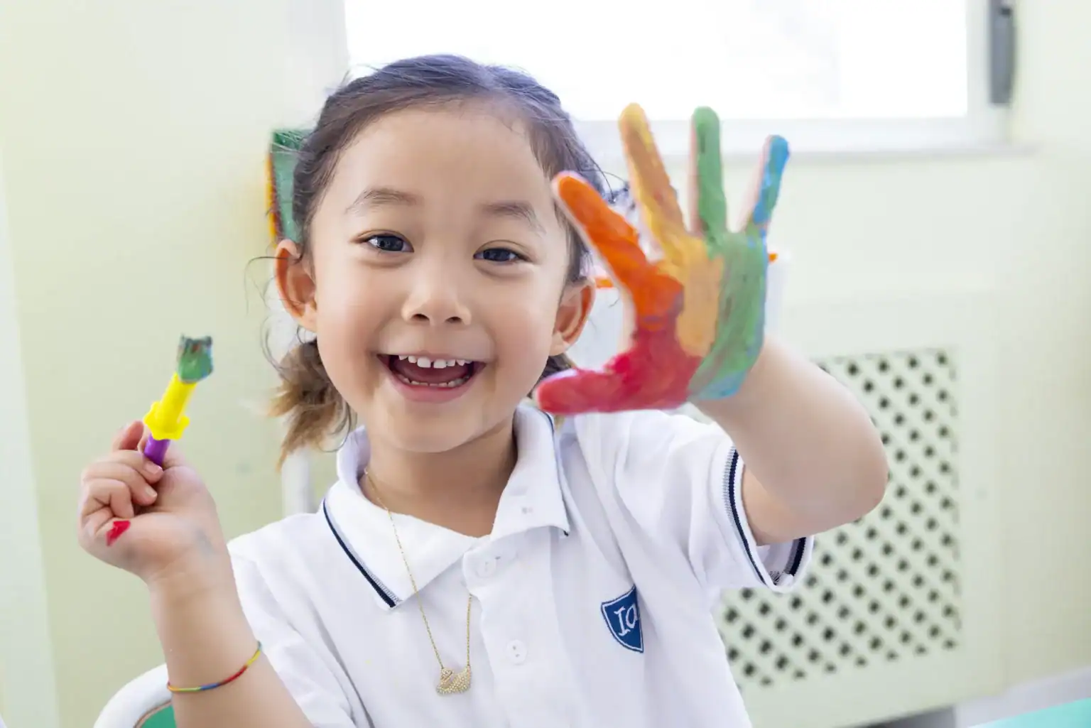 Bright young girl with painted hand, engaging in creative art activities at a World Schools setting.