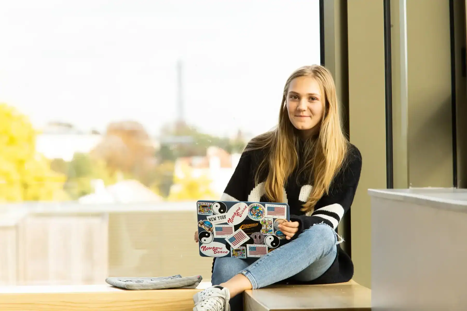 Young girl using a laptop at School with window view, emphasizing global education and international student opportunities.