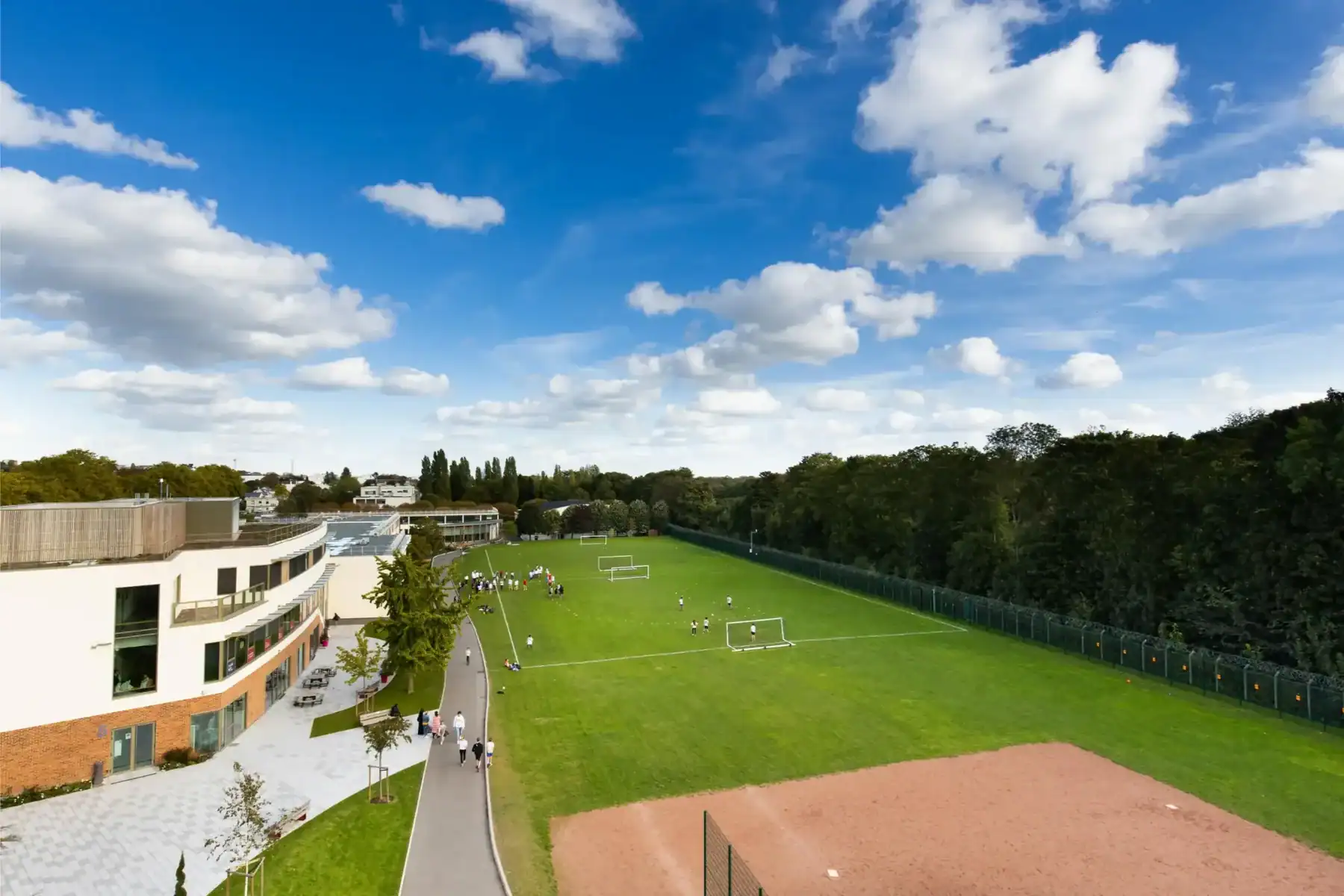 Bright school campus with sports fields, modern buildings, and green surroundings, ideal for international students.