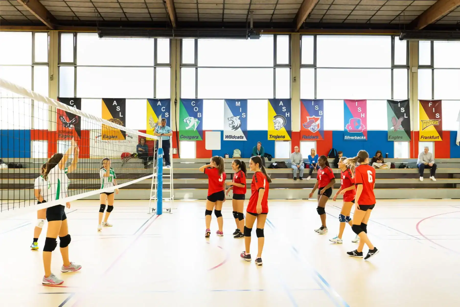 Junior volleyball game at top international school with vibrant banners and student athletes.