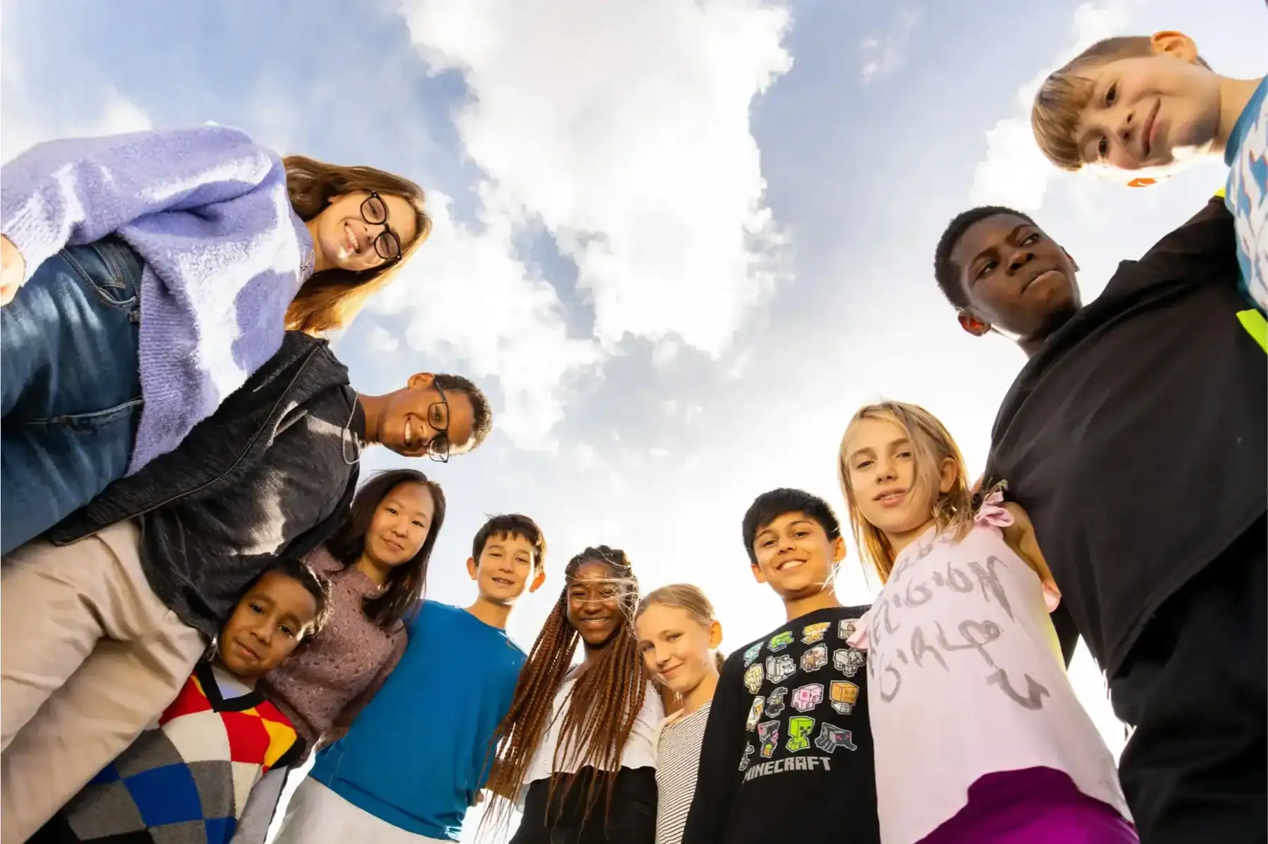 Diverse group of children and teenagers outdoors, representing inclusive international schooling environments.