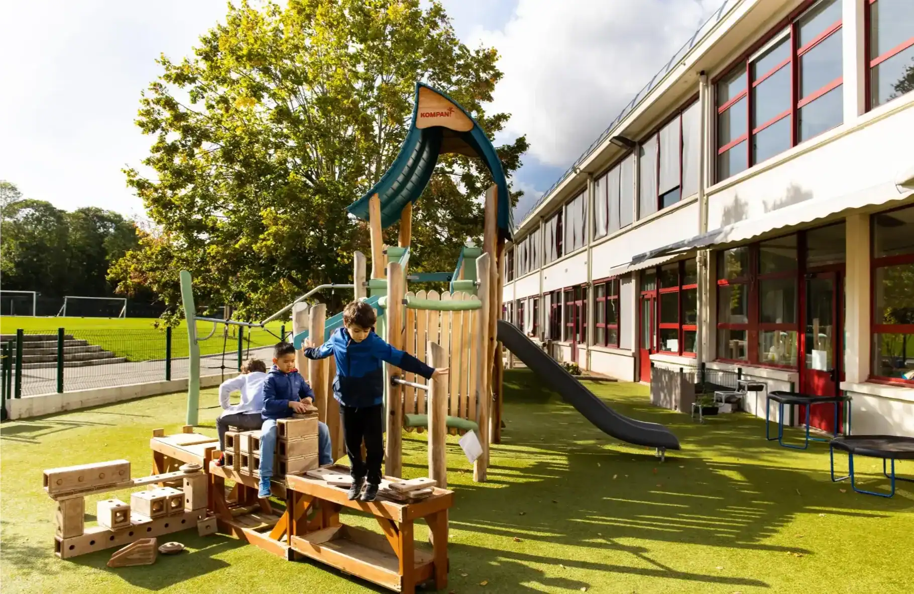Bright outdoor playground at World Schools with kids playing on slide and climbing structures for early childhood development.