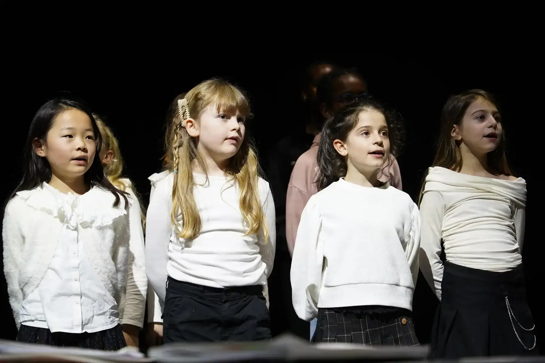 Group of diverse students singing on stage at St George's International School, Luxembourg.