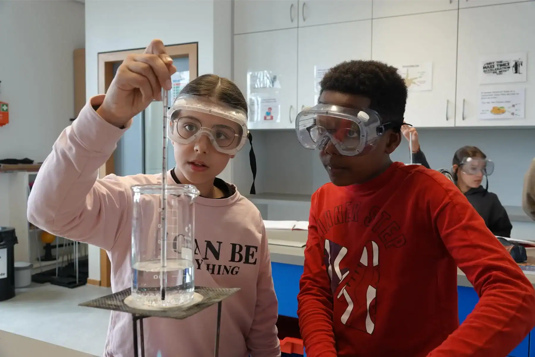 Students conducting a science experiment with safety goggles at St George's International School, Lu.