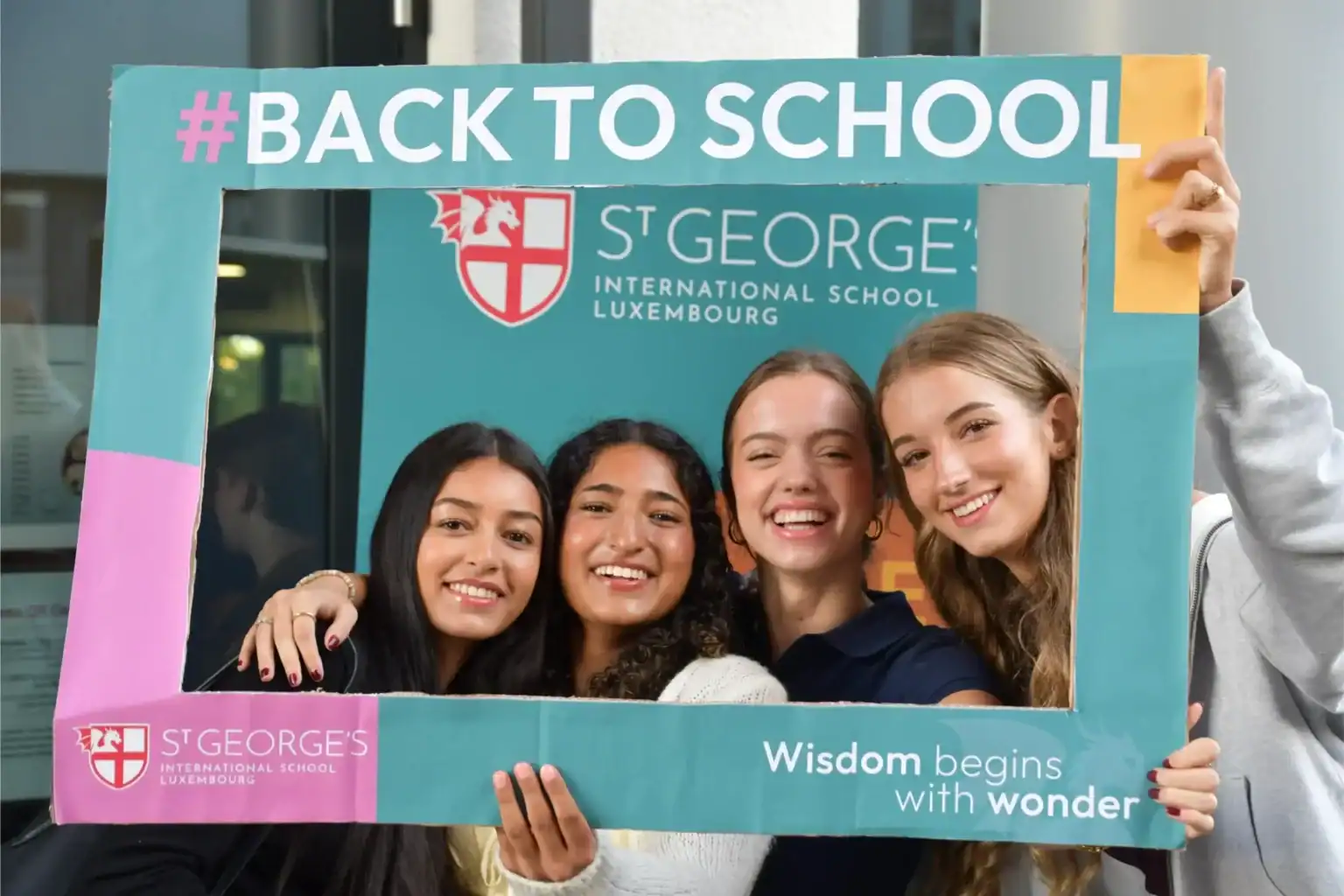 Group of diverse students holding a "#Back to School" frame at St George's Luxembourg.