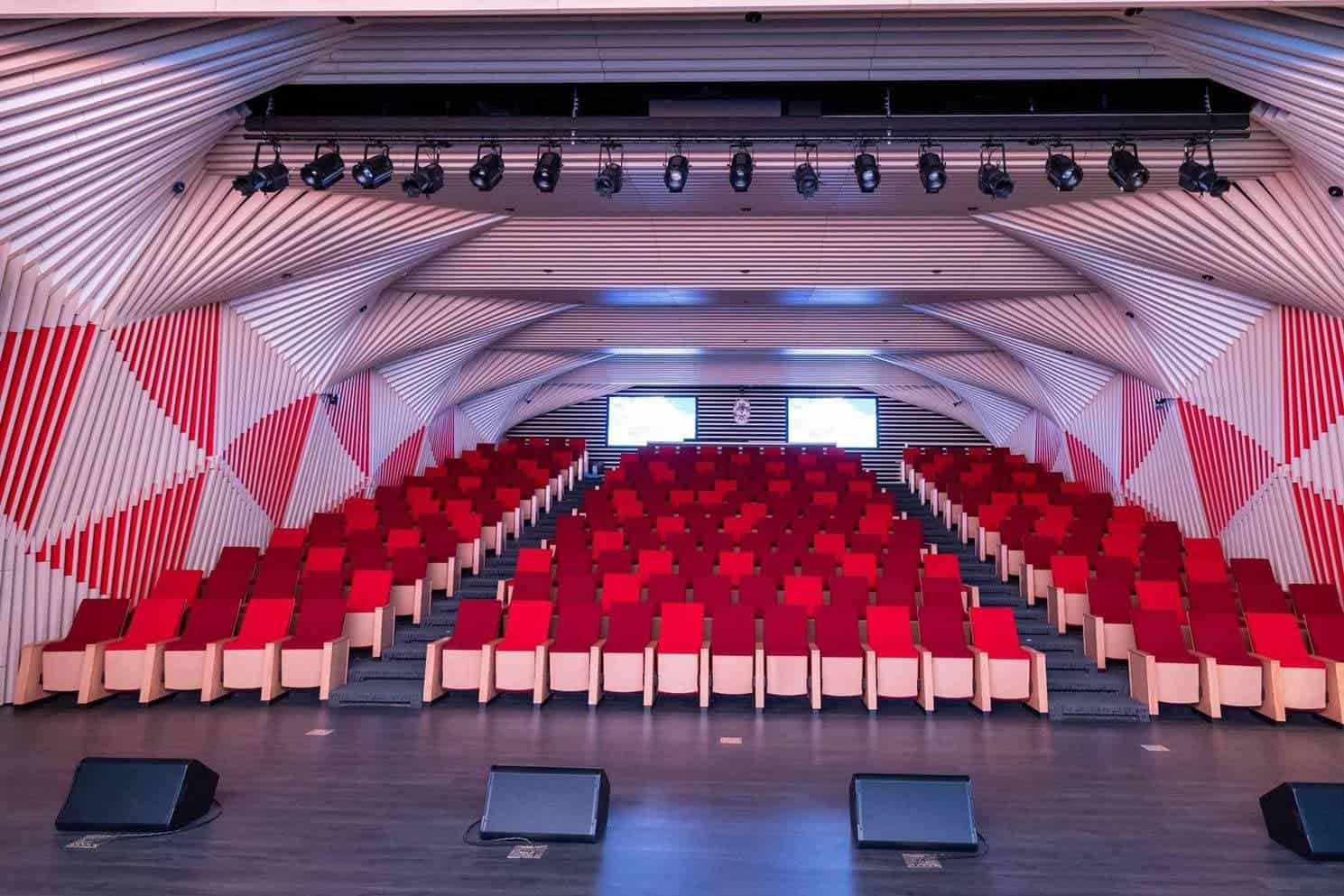 Auditorium at Dulwich College Seoul with red seats and modern design.