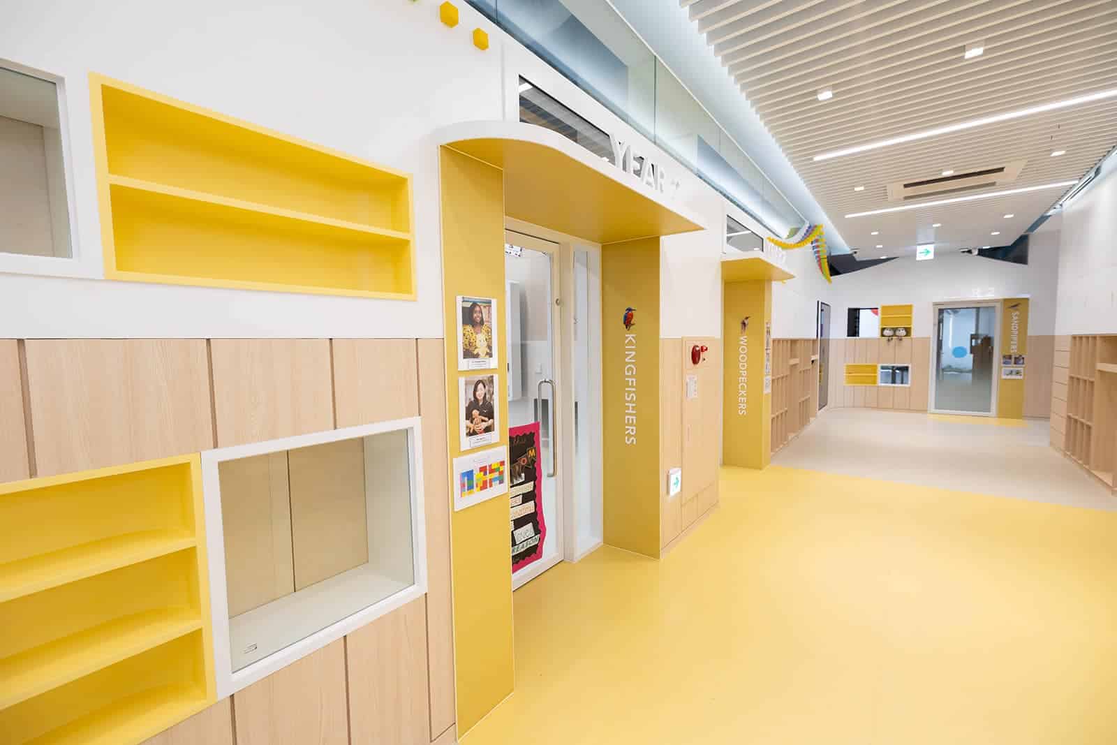 Bright school corridor with yellow and white decor at Dulwich College Seoul.