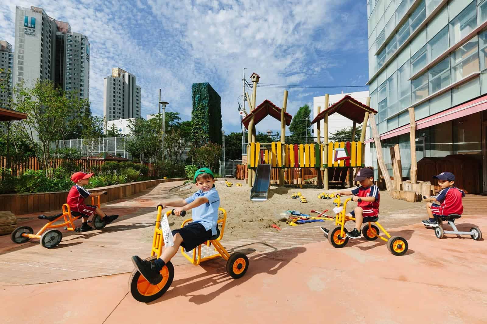 Children riding tricycles in the outdoor playground at Dulwich College Seoul.