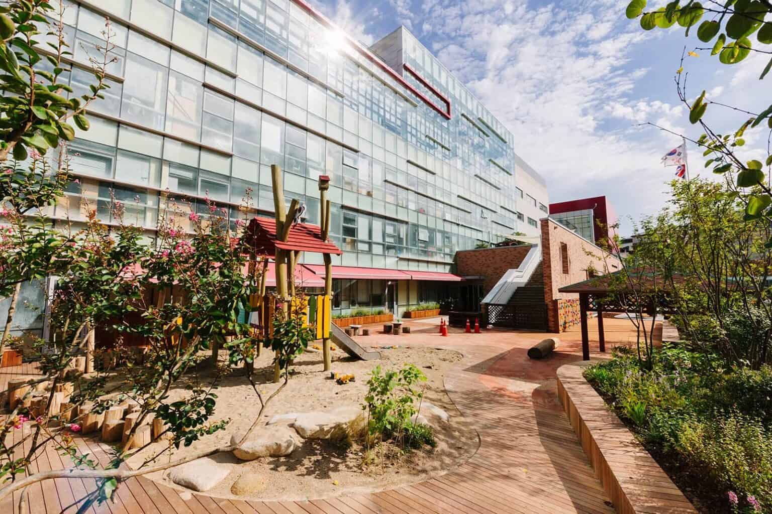 Dulwich College Seoul campus building with outdoor playground and garden.