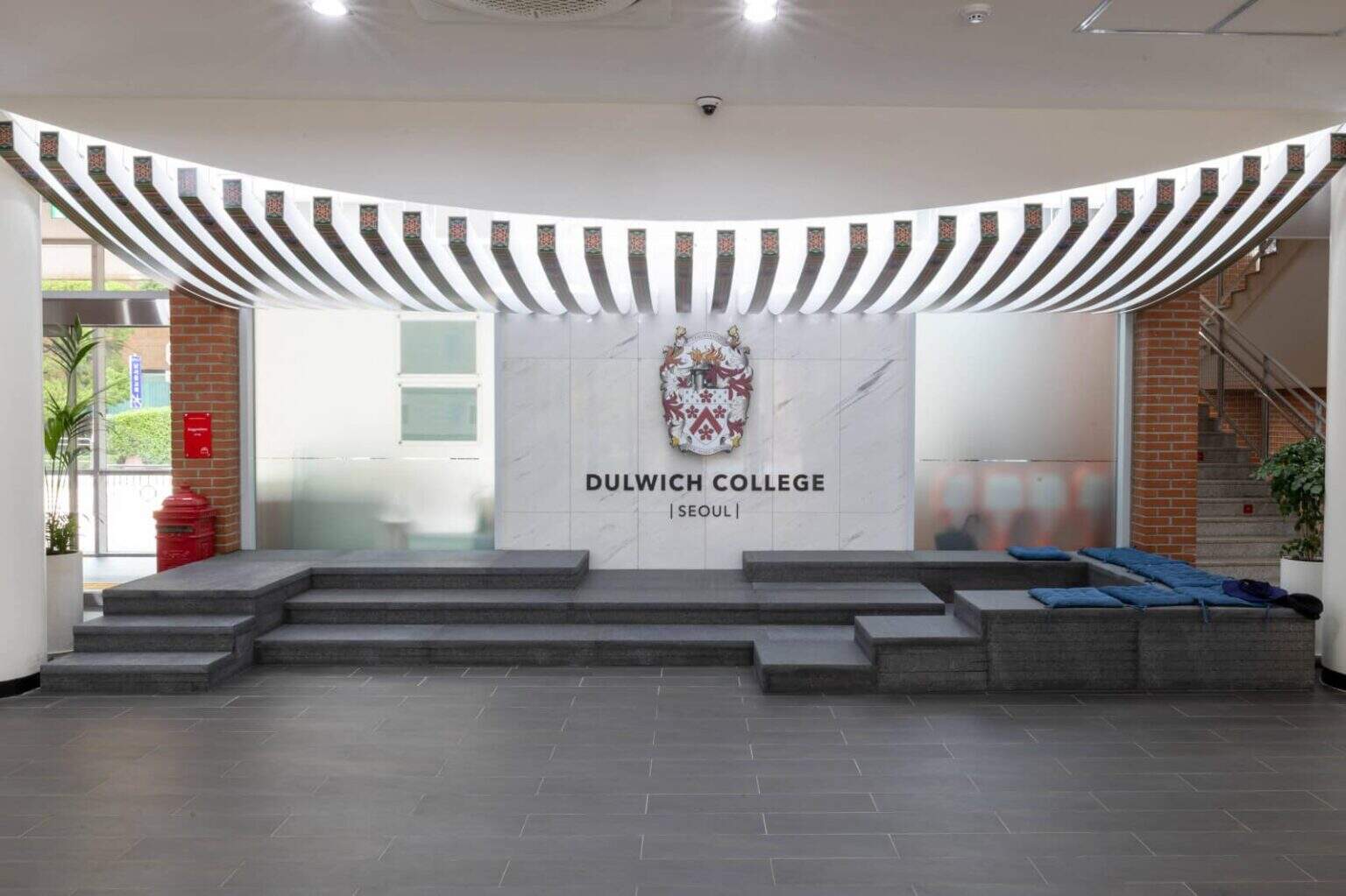 Modern entrance of Dulwich College Seoul with logo and welcoming steps.