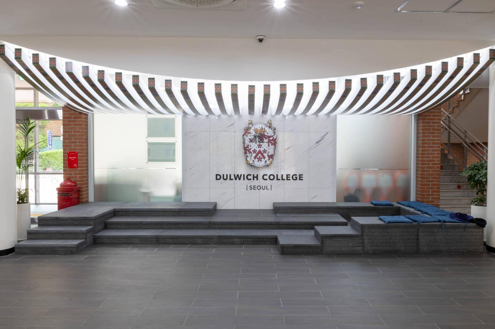 Modern entrance of Dulwich College Seoul with logo and welcoming steps.