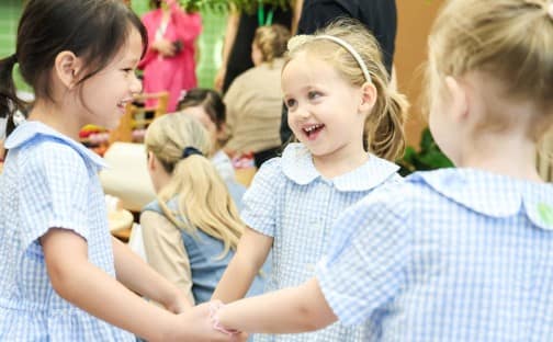 Happy children playing and holding hands at Dulwich College Beijing.