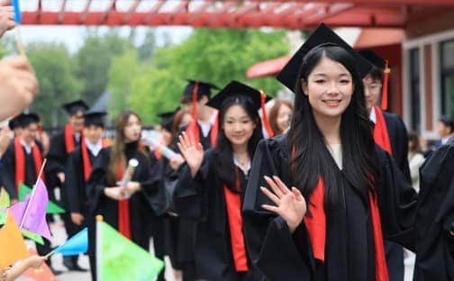 Graduates celebrating at Dulwich College Beijing in their caps and gowns.