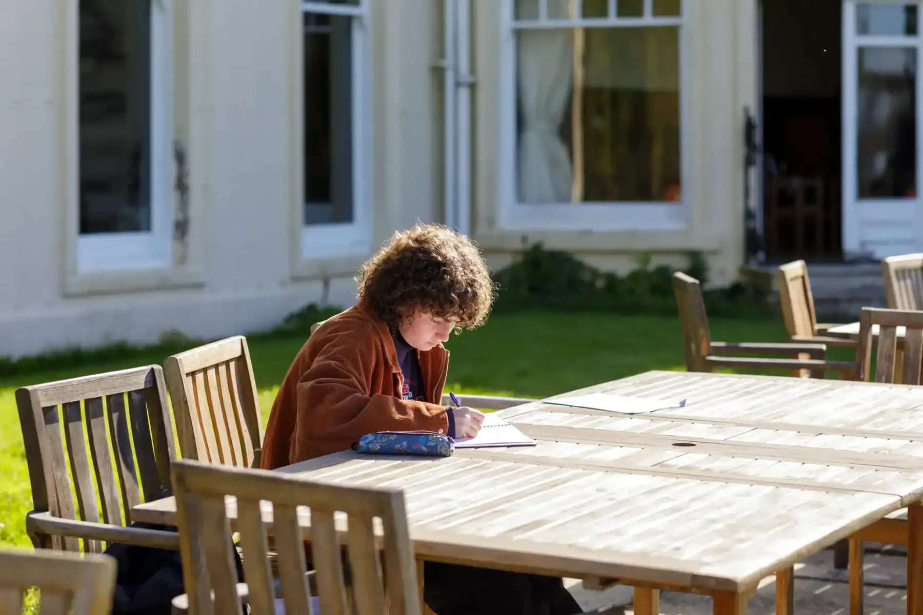 Outdoor classroom at Brockwood Park School with student studying on a sunny day.
