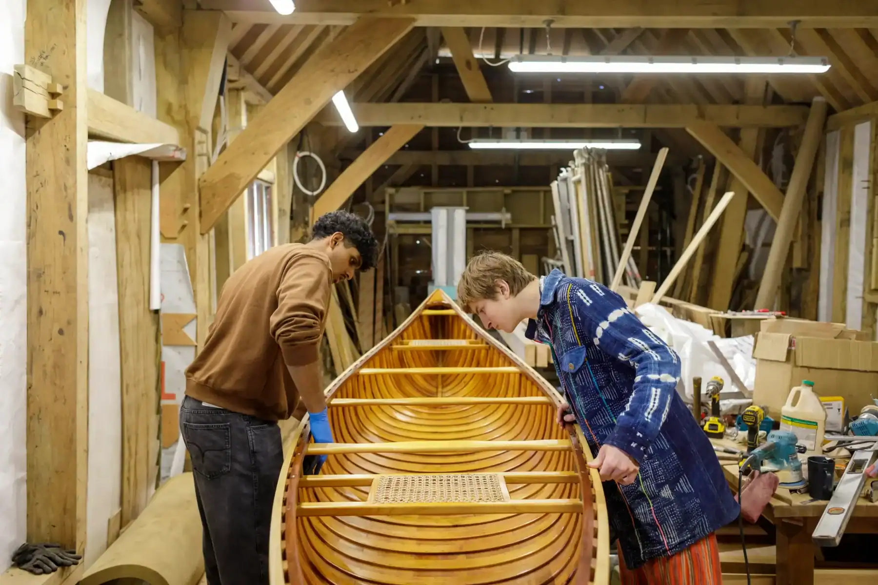Students building a wooden boat in a workshop at Brockwood Park School.