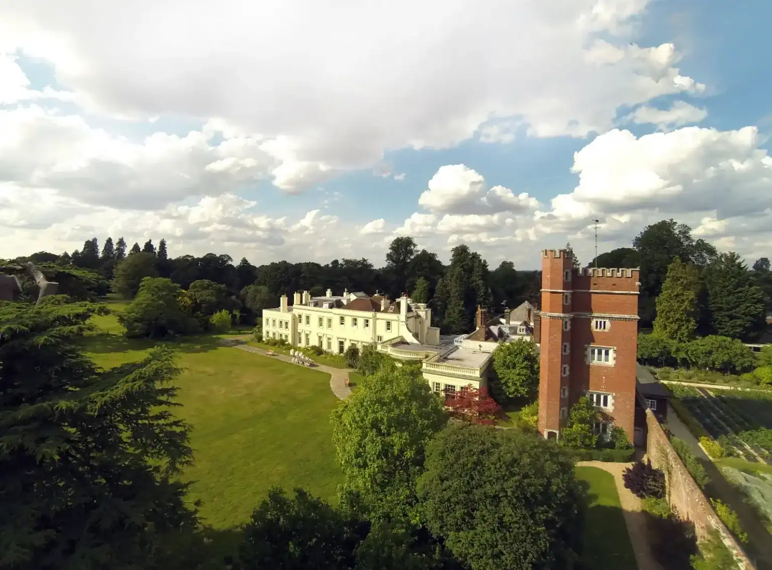 Brockwood Park School historic campus with lush green grounds and distinctive red brick tower.