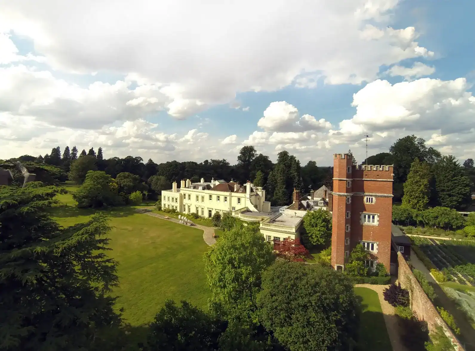 Brockwood Park School historic campus with lush green grounds and distinctive red brick tower.