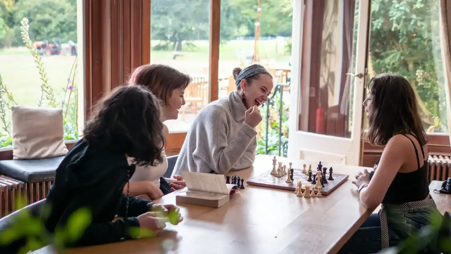 Students playing chess at Brockwood Park School in a bright, outdoor setting.
