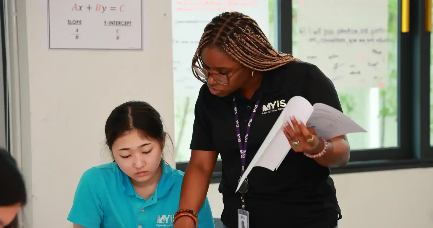 Teacher assisting student with homework at MYIS International School.