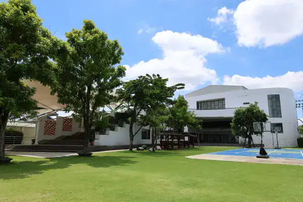 School campus with lush greenery, outdoor sports area, and contemporary architecture.