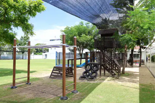 Playground at MYIS International School with trees, shade, and play structures.