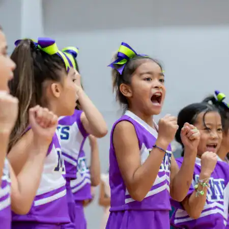 Young girls in purple cheerleading uniforms showing excitement and enthusiasm.