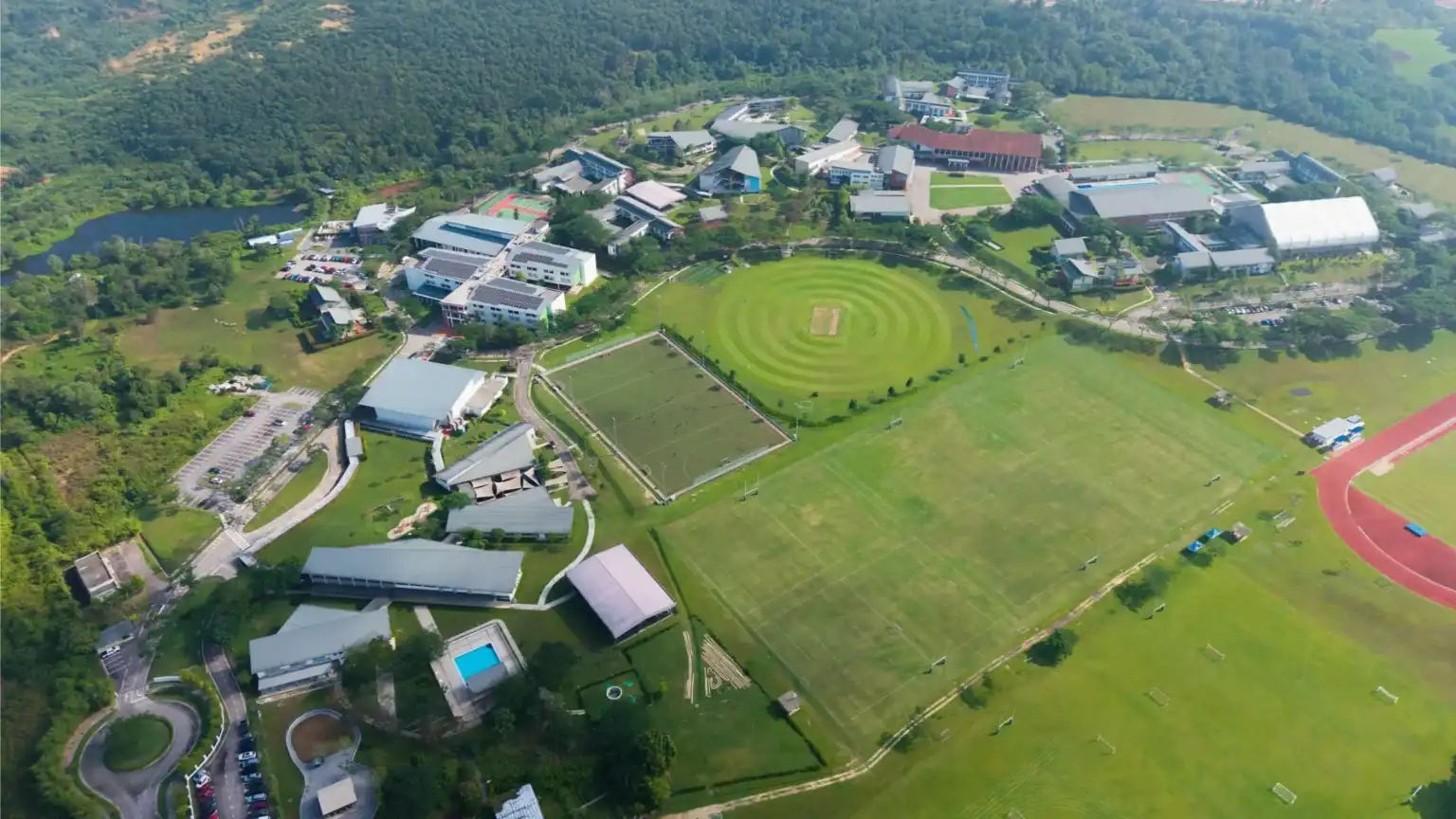 A lush green school campus with sports fields and modern facilities.