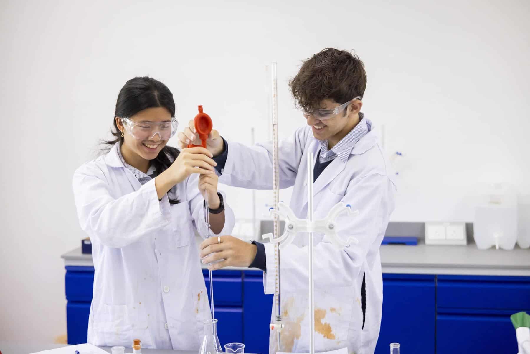 A student and a teacher conducting a science experiment in a school laboratory.