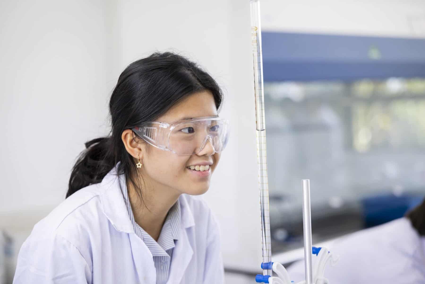 A woman scientist wearing safety goggles conducting an experiment in a laboratory.