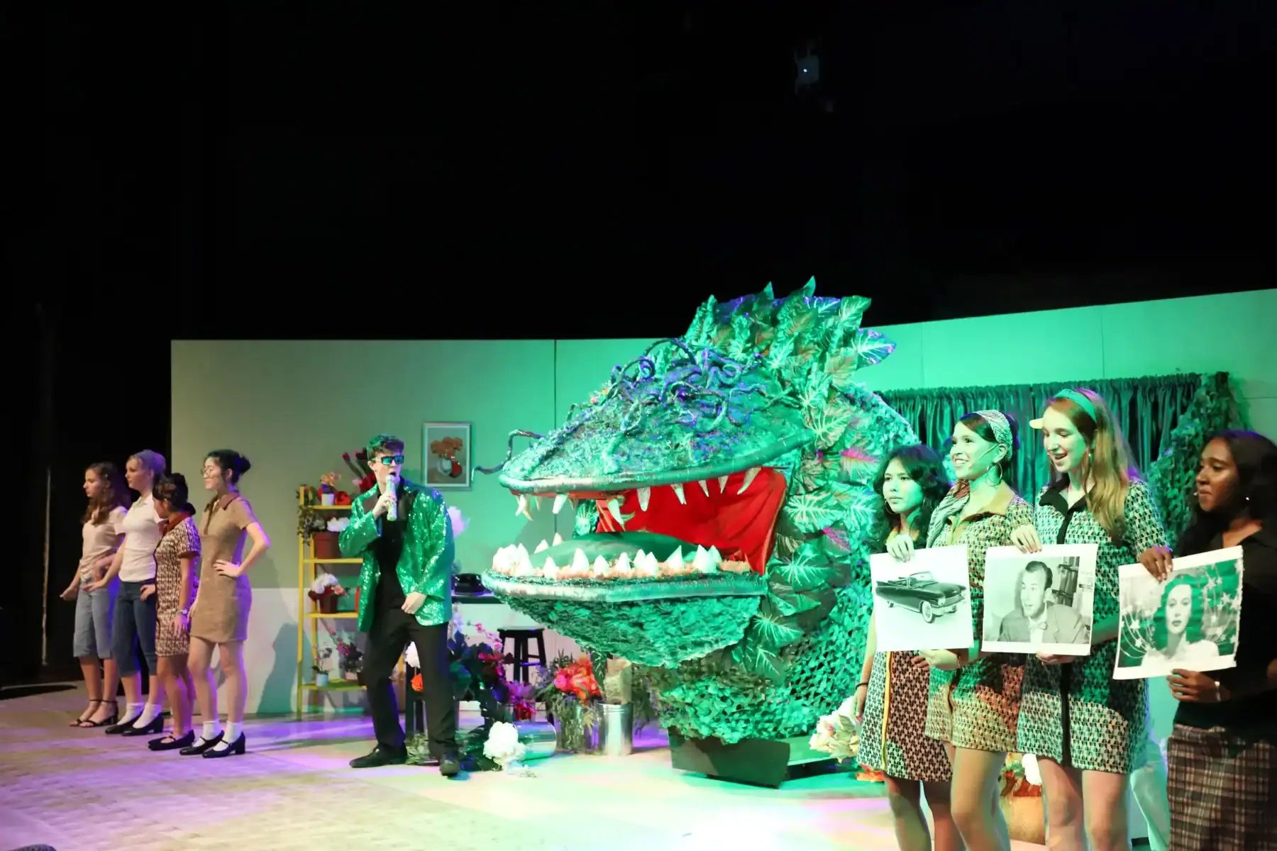 Diverse students performing with a dragon puppet on stage at a school event.