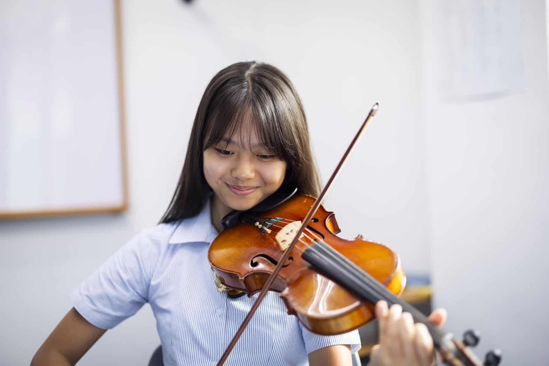 Elegant young girl playing violin in a classroom, showcasing music education at a world school.