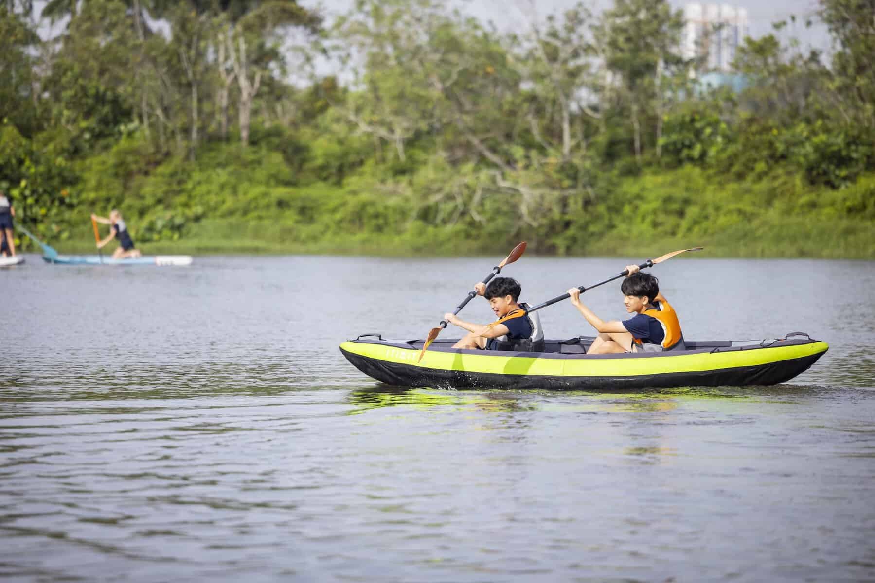 Enjoying kayaking on a calm river with children and nature in the background.