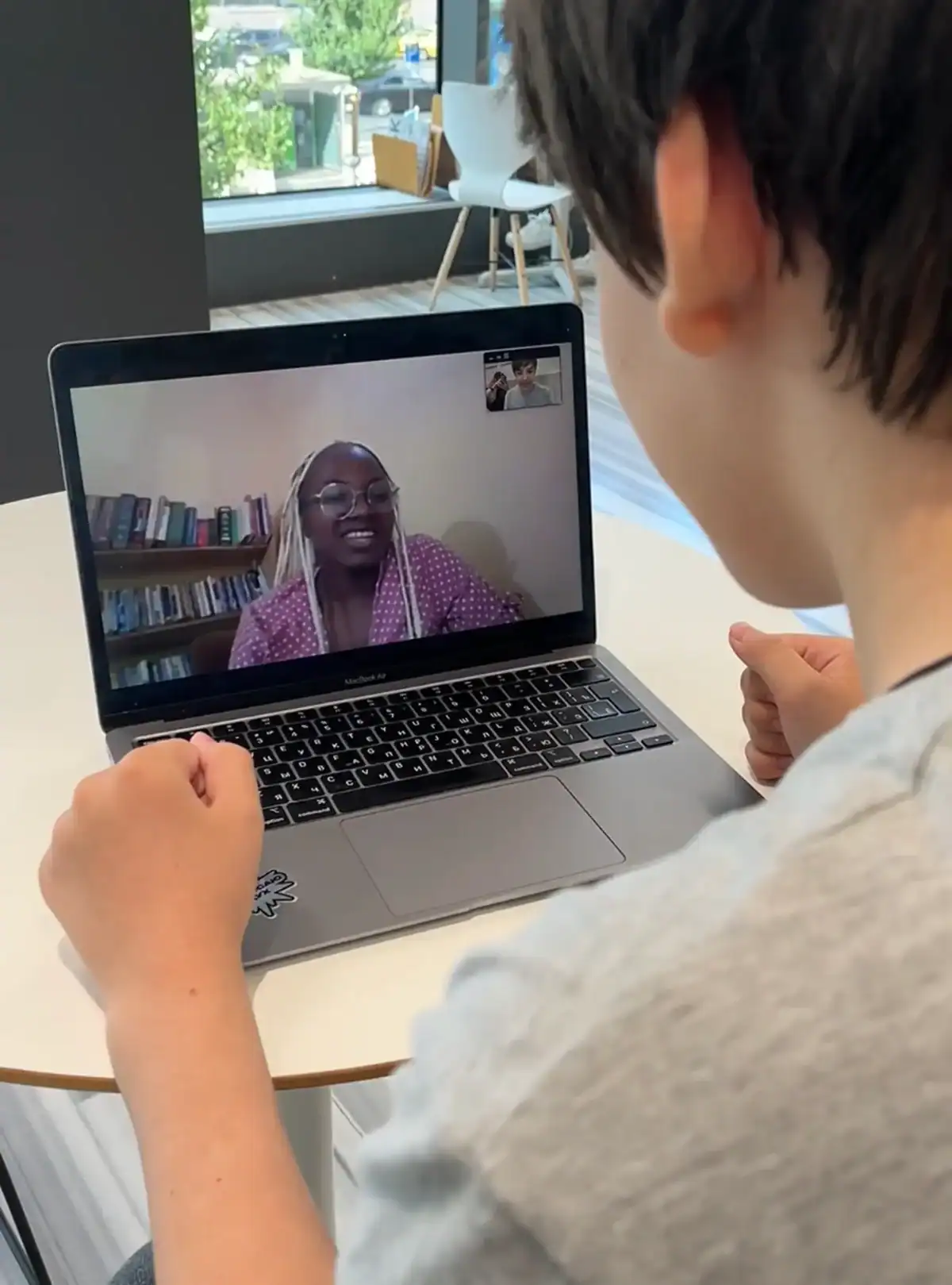 Child engaging in a virtual learning session with a teacher on a laptop.