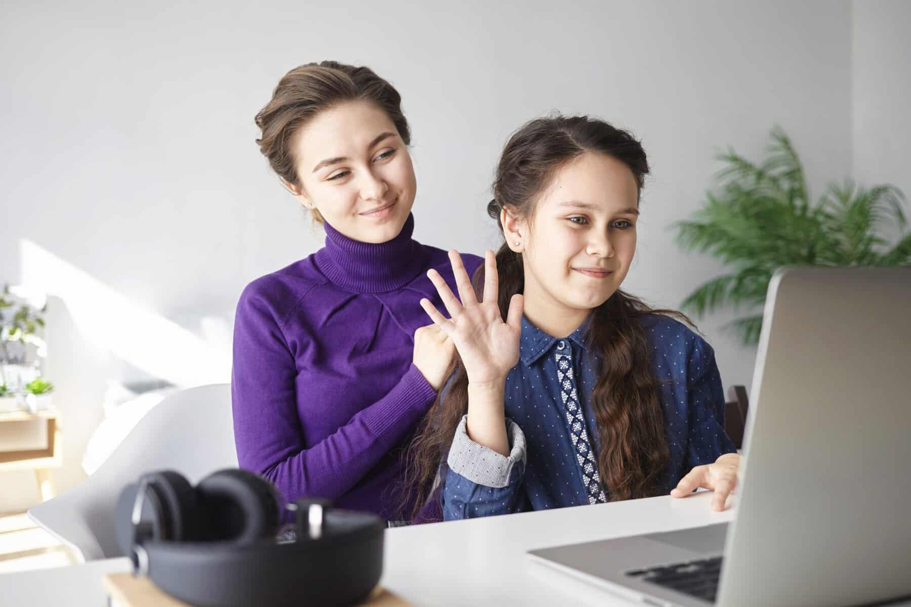 Two girls engaging in online learning with a laptop at home.