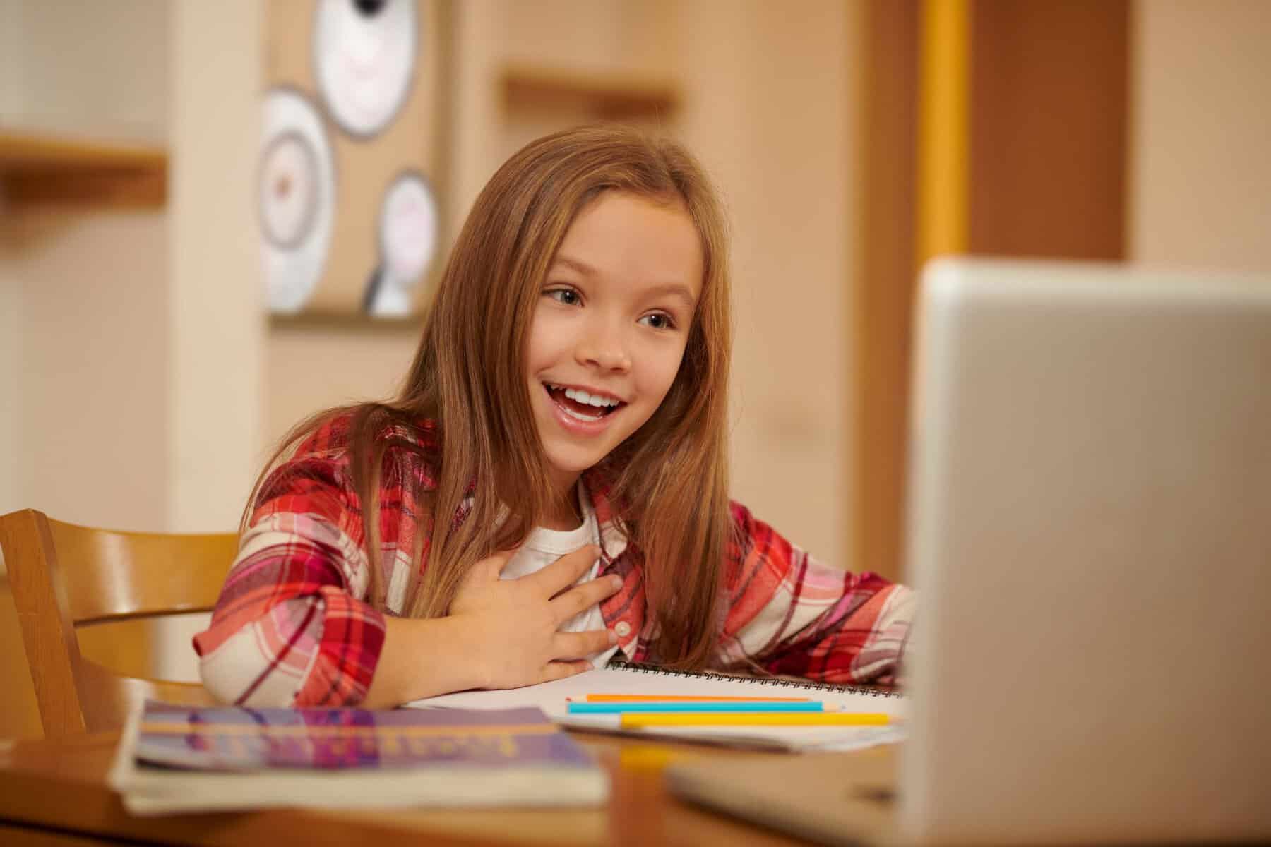Young girl engaging in online learning at home with a laptop.