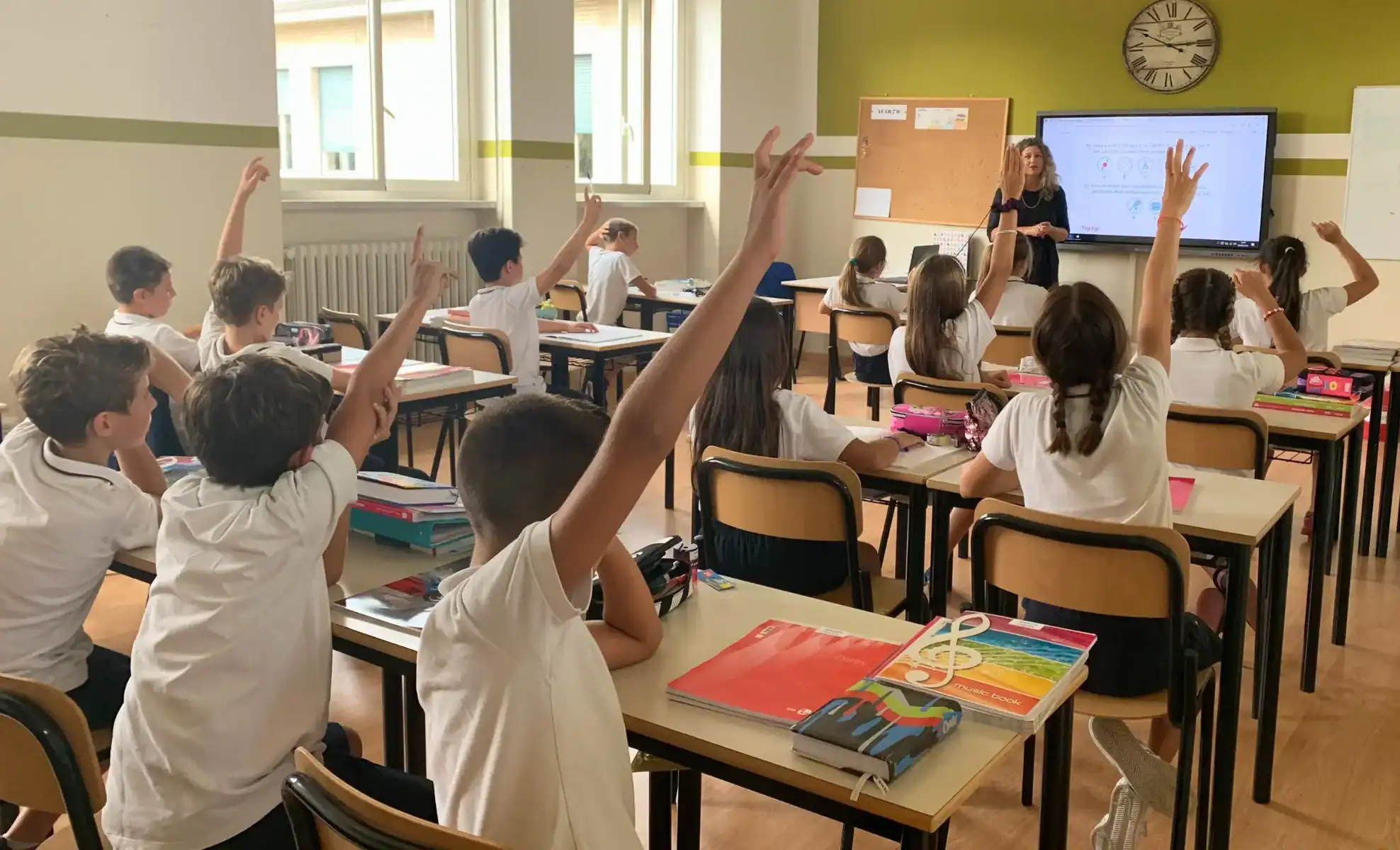 Students in a classroom raising hands during a lesson at Andersen International School.