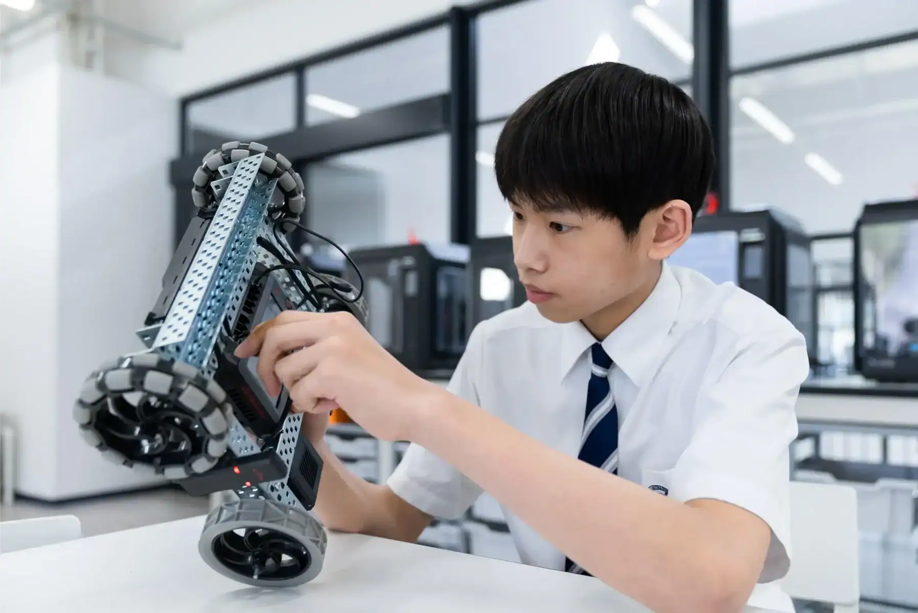 Young student working on robotics project in modern classroom.