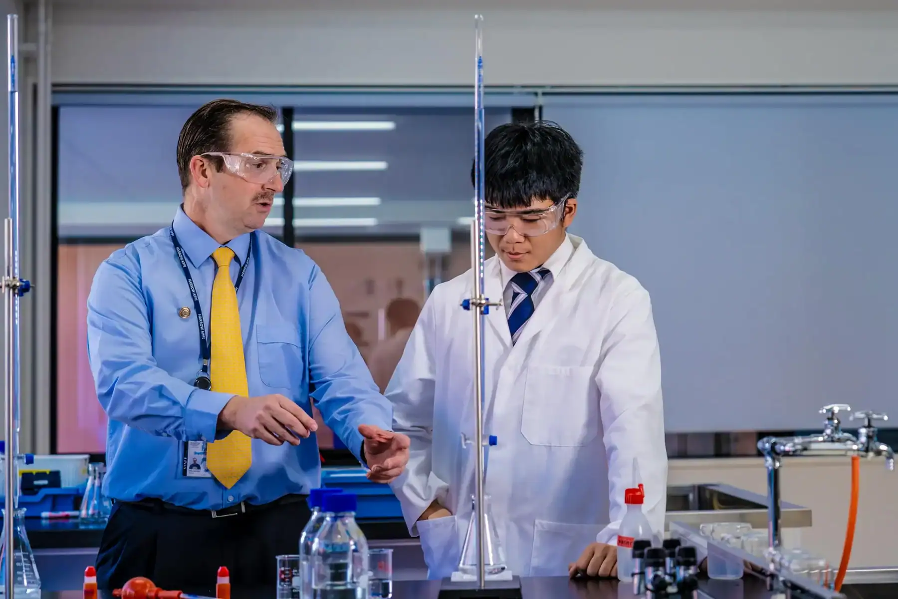 Science teacher and student conducting experiment in laboratory at Harrow International School Appi.