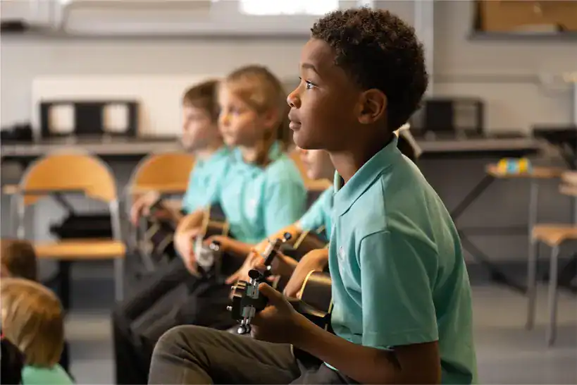 Young students playing guitars in a classroom at The British School Warsaw.