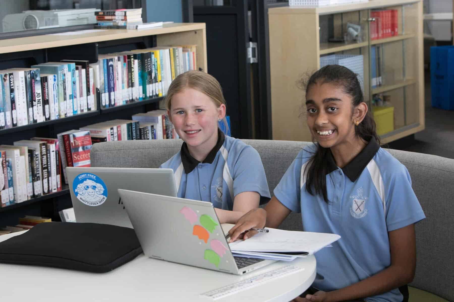 Two students using laptops in a school library at Ivanhoe Grammar School.